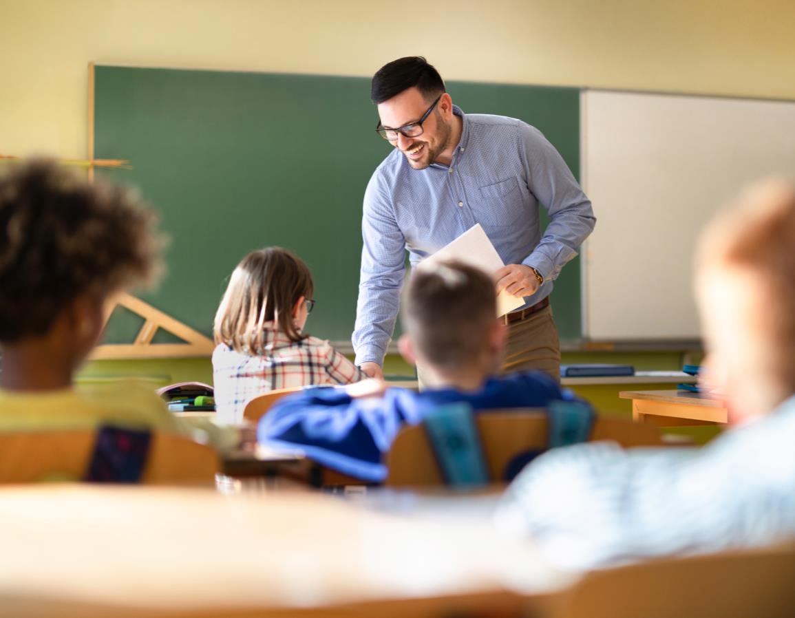 A teacher helping students at their desks in a classroom